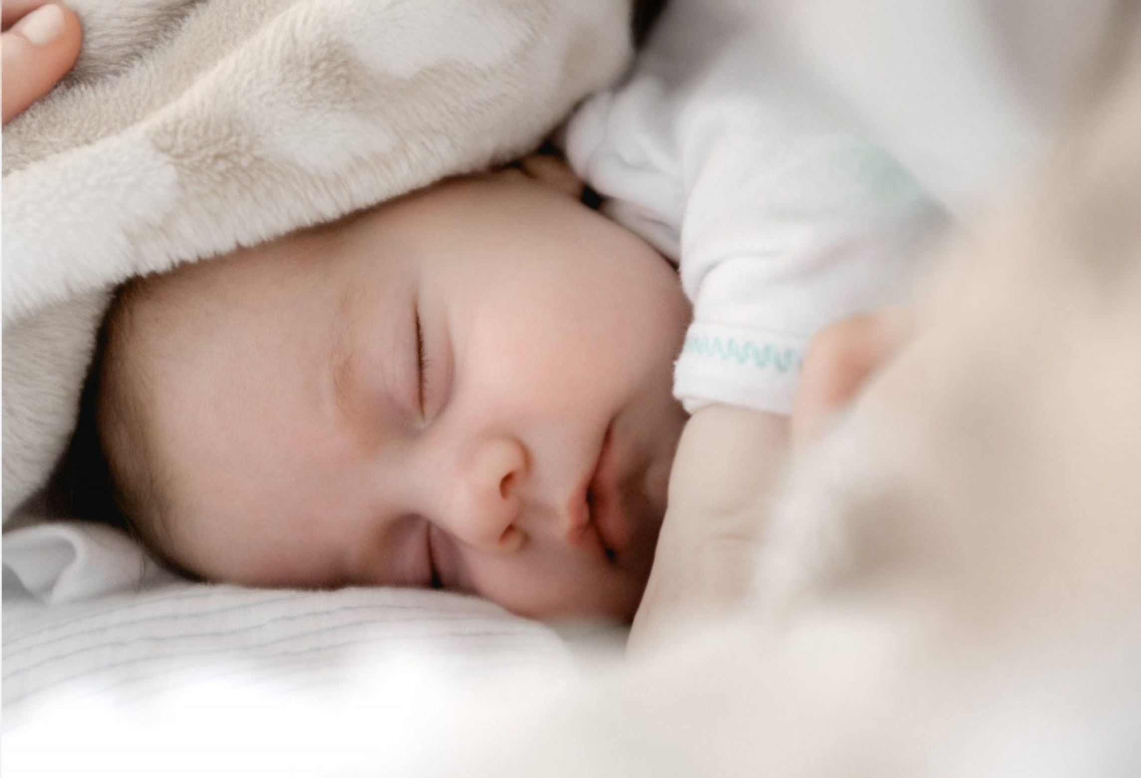 A peaceful baby sleeps under a soft blanket