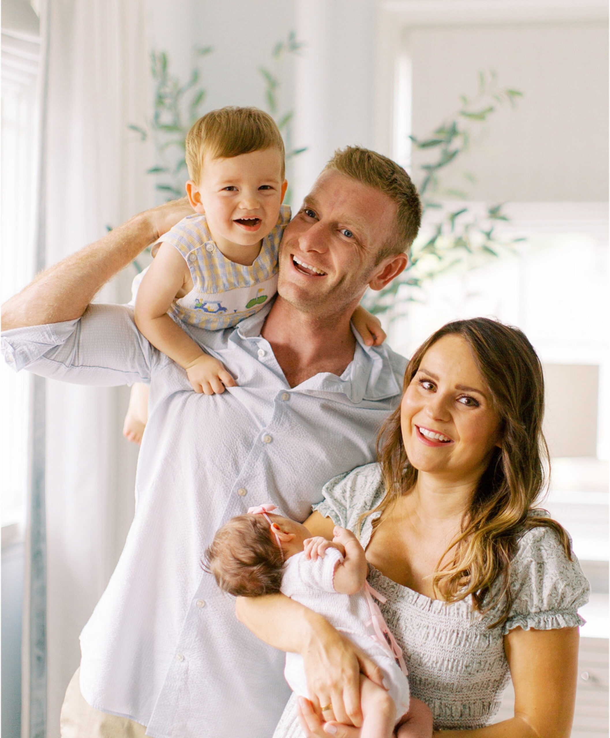 A smiling family poses together in a bright room