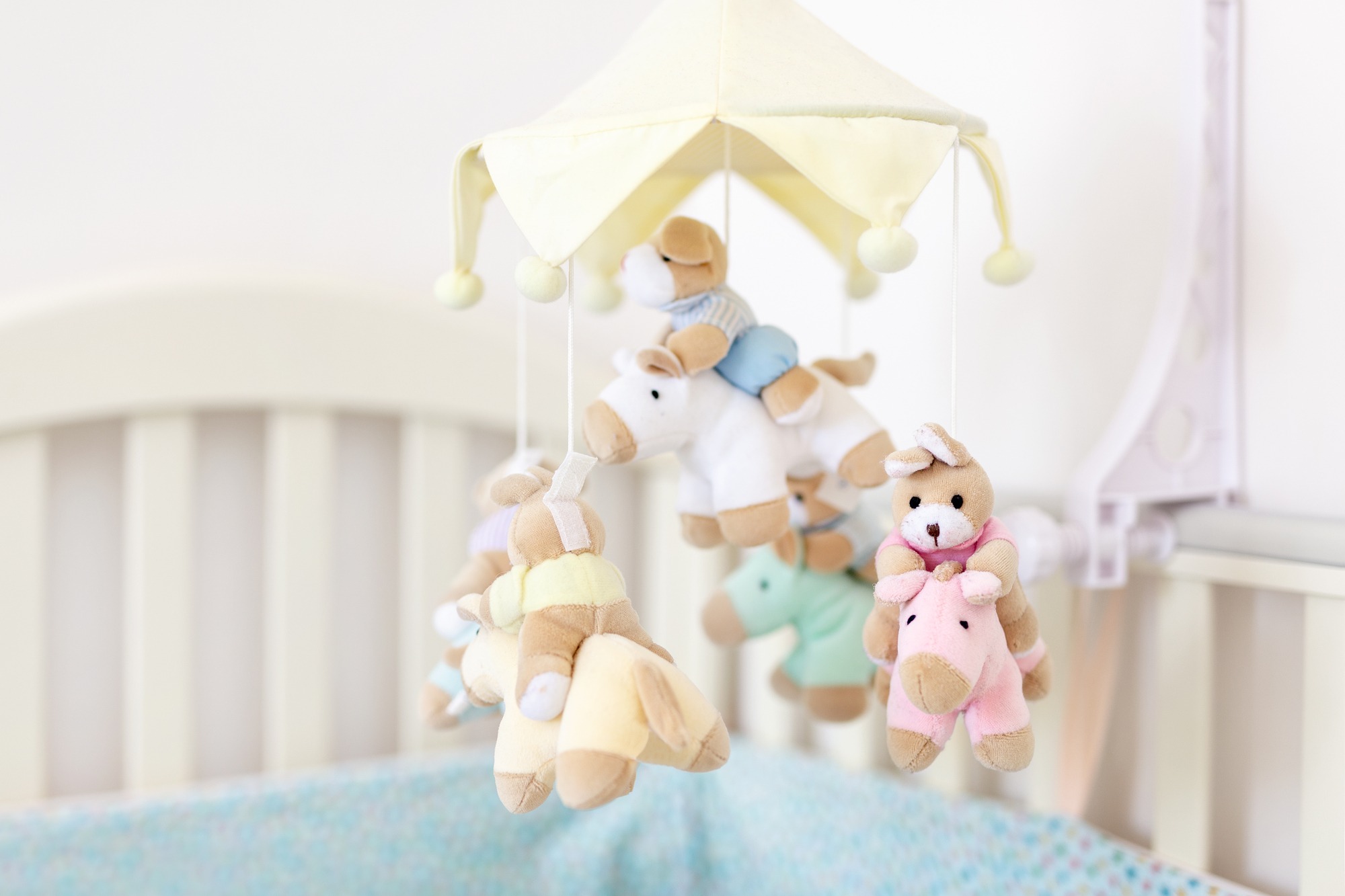 Close-up baby crib with musical animal mobile at nursery room.