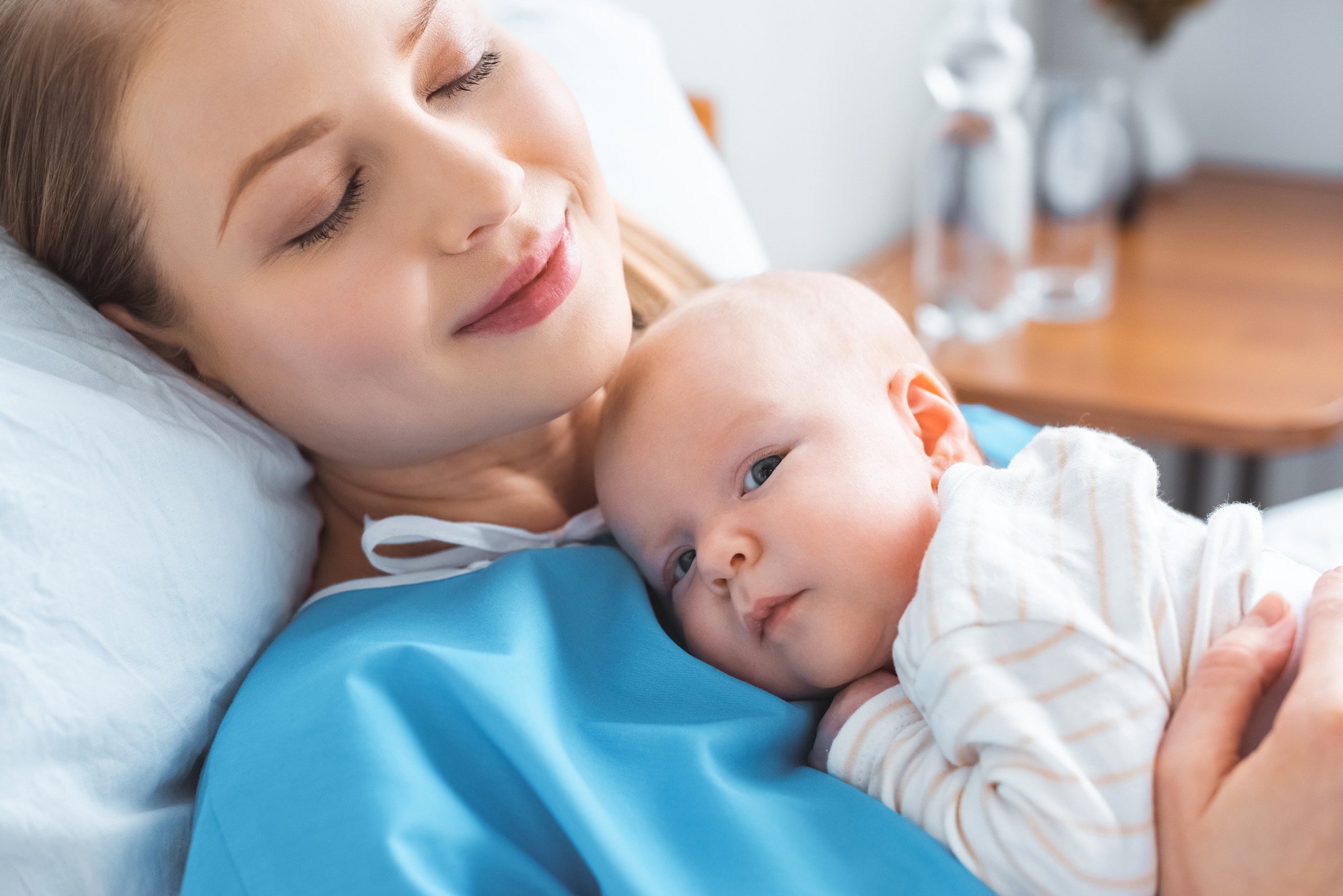 Happy young mother with closed eyes lying with adorable