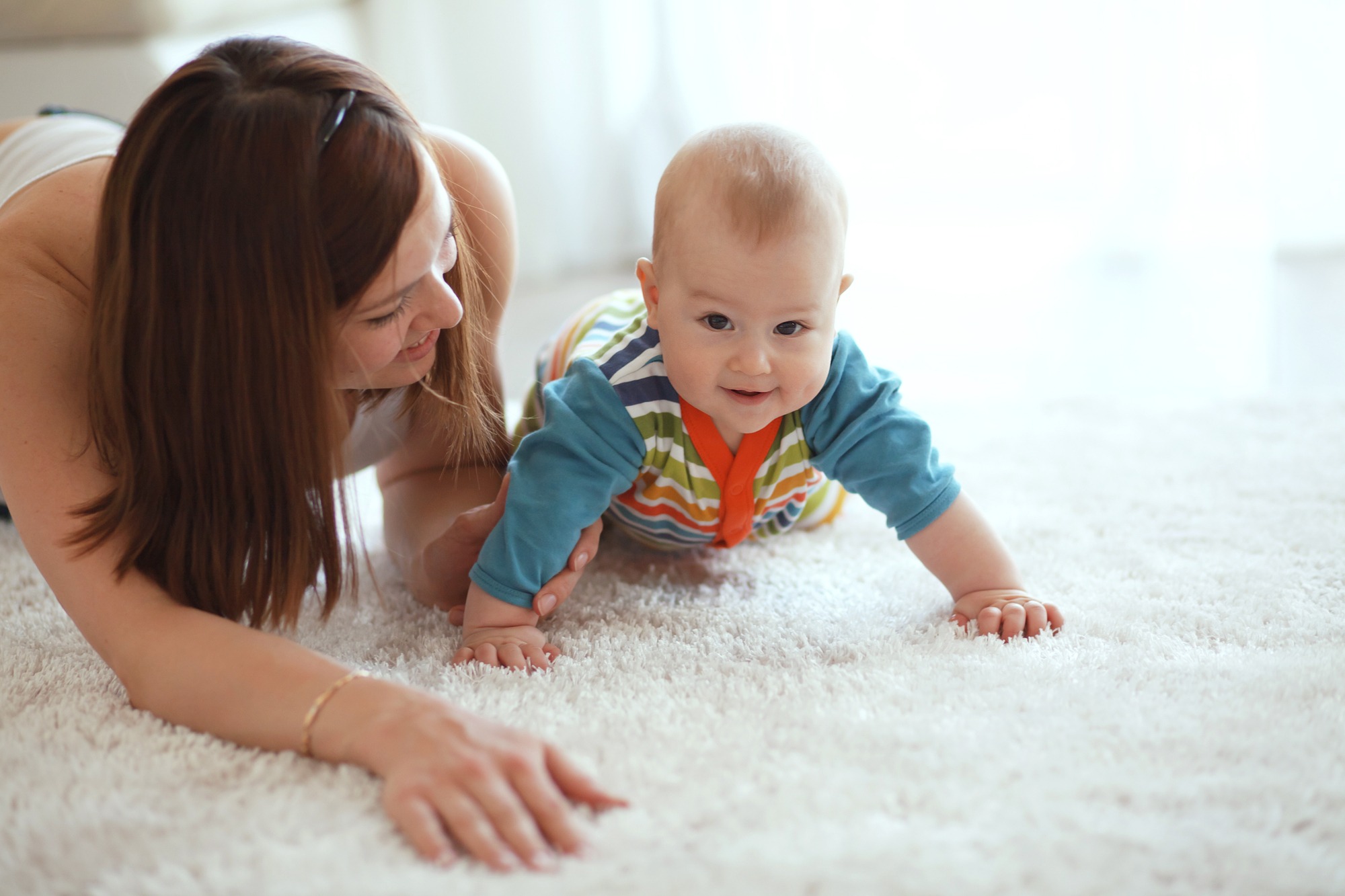 Mother with her baby playing on a carpet at home