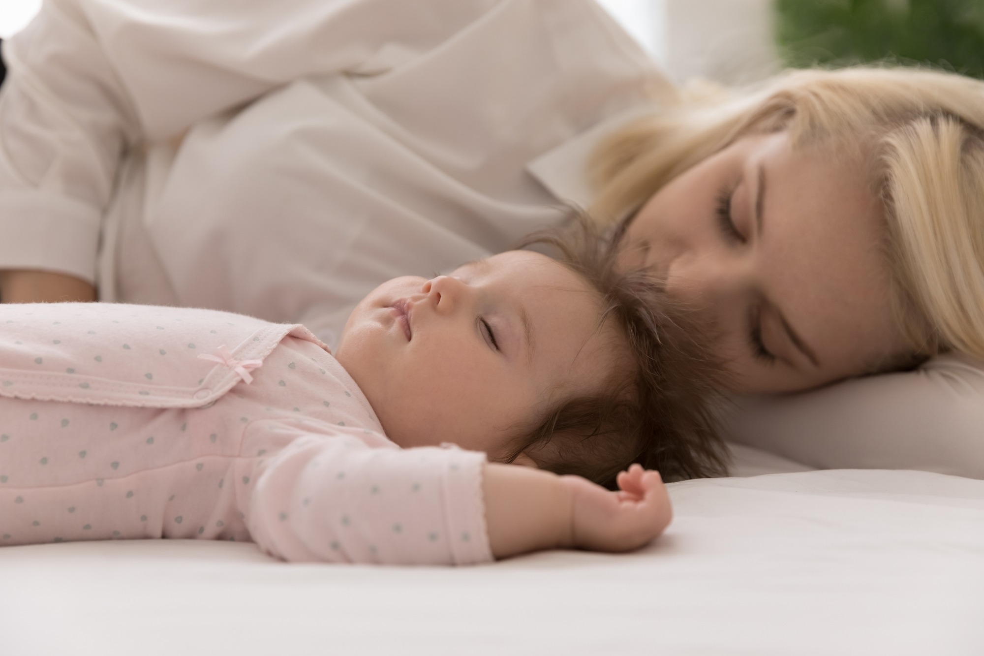 Close up shot peaceful newborn baby and young mom sleeping in bed